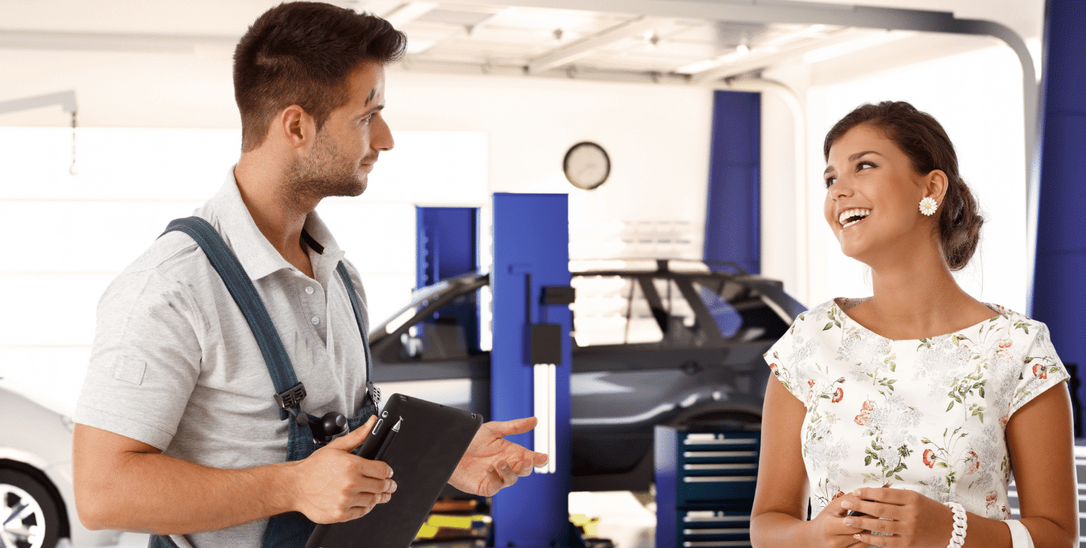 Ein Kfz-Mechaniker und eine Kundin unterhalten sich.